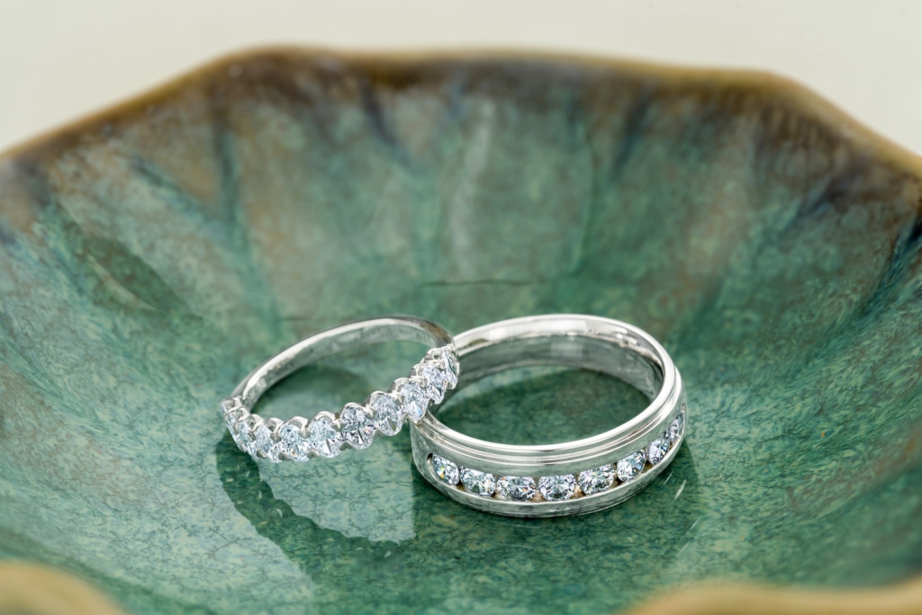 Two diamond wedding bands in white gold displayed in a green leaf-shaped bowl.