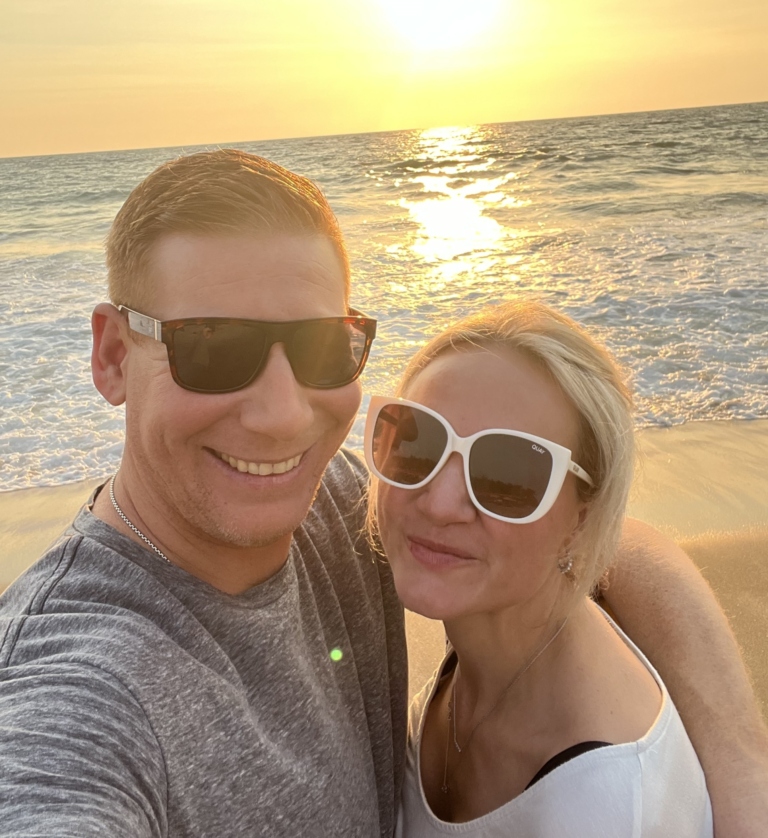 Frankie and Erin smiling at the beach during sunset.